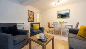 A living room with two grey sofas, a wooden coffee table, and a dining area with a white table and chairs. - GuestReady - Charming haven in Knowledge Quarter (Liverpool)