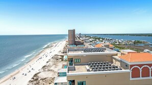 Ein Hotel an der Küste mit Blick auf den Strand, mehreren Balkonen und einem Parkplatz.