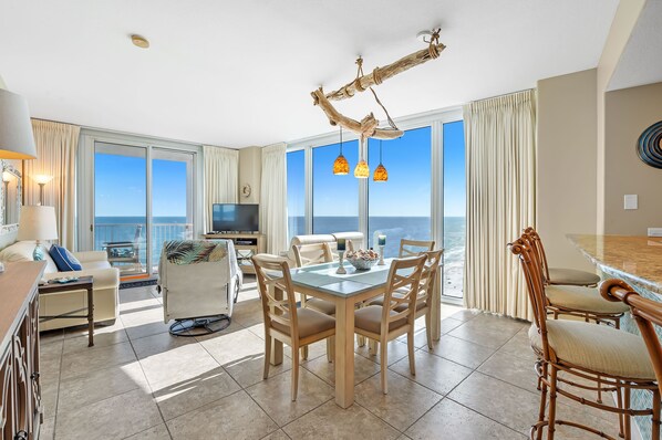 Relax in this spacious living area with a dining table, sofa, and television, offering a view of the ocean.