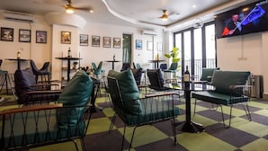 Un área de estar moderna con sillones acolchados verdes, un televisor de pantalla plana y obras de arte en las paredes.