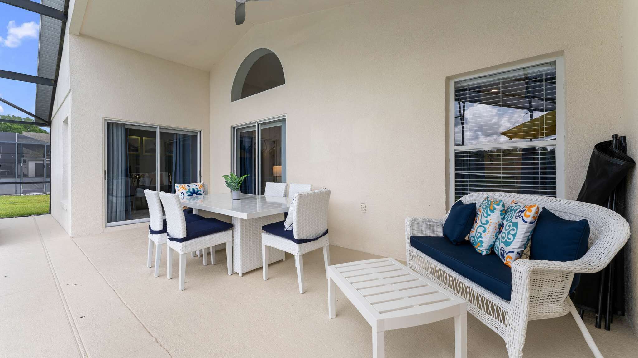 An outdoor patio area with a table and chairs, a sofa, and a small table.