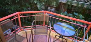 Un balcon avec une balustrade rouge, une table ronde et deux chaises.
