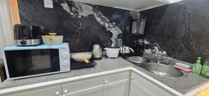 Une cuisine équipée d’un four à micro-ondes, d’une cuisinière, d’une bouilloire et d’un évier.