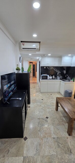 A modern living room with a flat-screen TV, a coffee table, and a seating area.