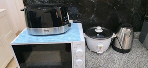 A kitchen with a microwave, a slow cooker, and a coffee maker on a countertop.