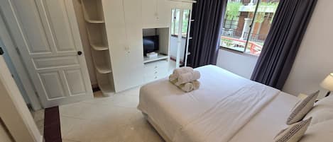 A hotel room with a bed, a wardrobe, and a view of the outside.