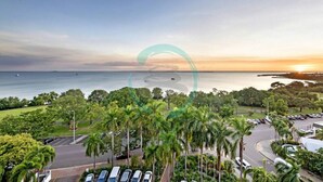 A coastal view with a parking lot, palm trees, and a body of water. - ZEN88 ESPLANADE - Hotel Suite Ocean View (Darwin)