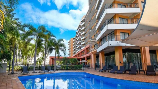 A hotel with a swimming pool, palm trees, and a covered outdoor seating area. - ZEN88 ESPLANADE - Hotel Suite Ocean View (Darwin)