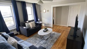 A modern living room with a dark grey sofa, a round coffee table, and a ceiling fan.