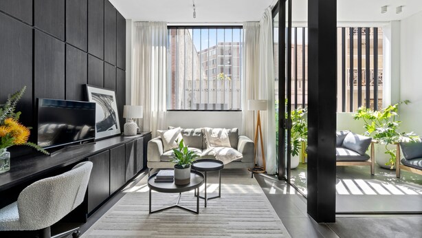 Un salon moderne avec un canapé, un téléviseur, une table basse et une plante.