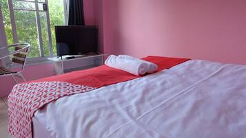 Una habitación de hotel con una cama, un escritorio con televisor y una silla.