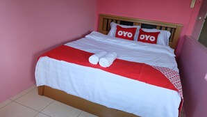 A neatly made bed with white and red bedding, two pillows with "OYO" text, and two rolled towels. - POP 75429 101 Place Navanakorn (Khlong Luang)