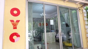 A building with large glass sliding doors, a yellow exterior wall, and a red and gold sign with the letters "OYO". - POP 75429 101 Place Navanakorn (Khlong Luang)