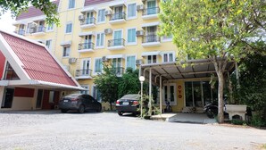 A multi-story building with balconies, a covered entrance, and parked cars. - POP 75429 101 Place Navanakorn (Khlong Luang)