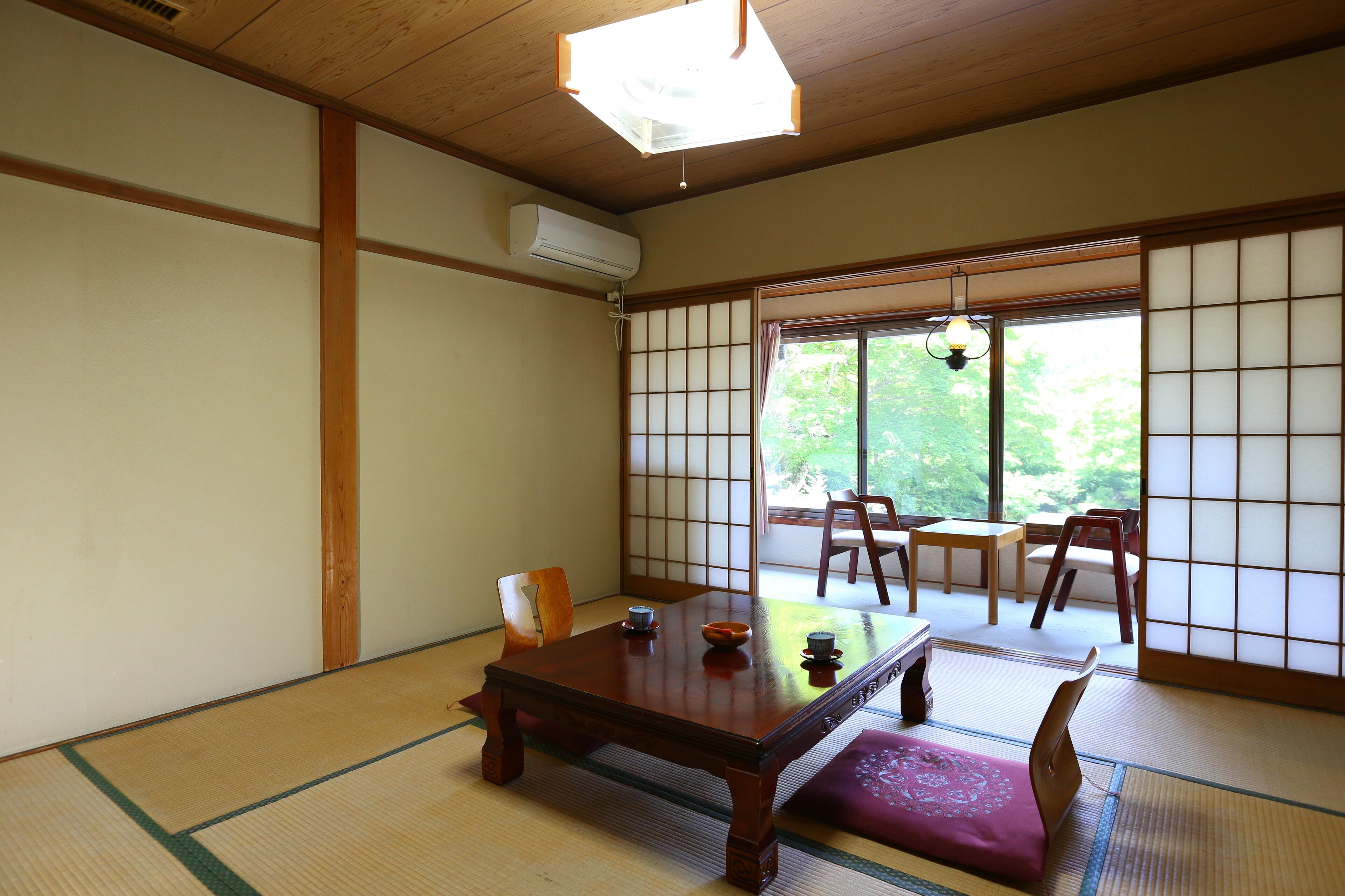Una habitación japonesa tradicional con suelo de tatami, una mesa de madera y puertas correderas shoji.