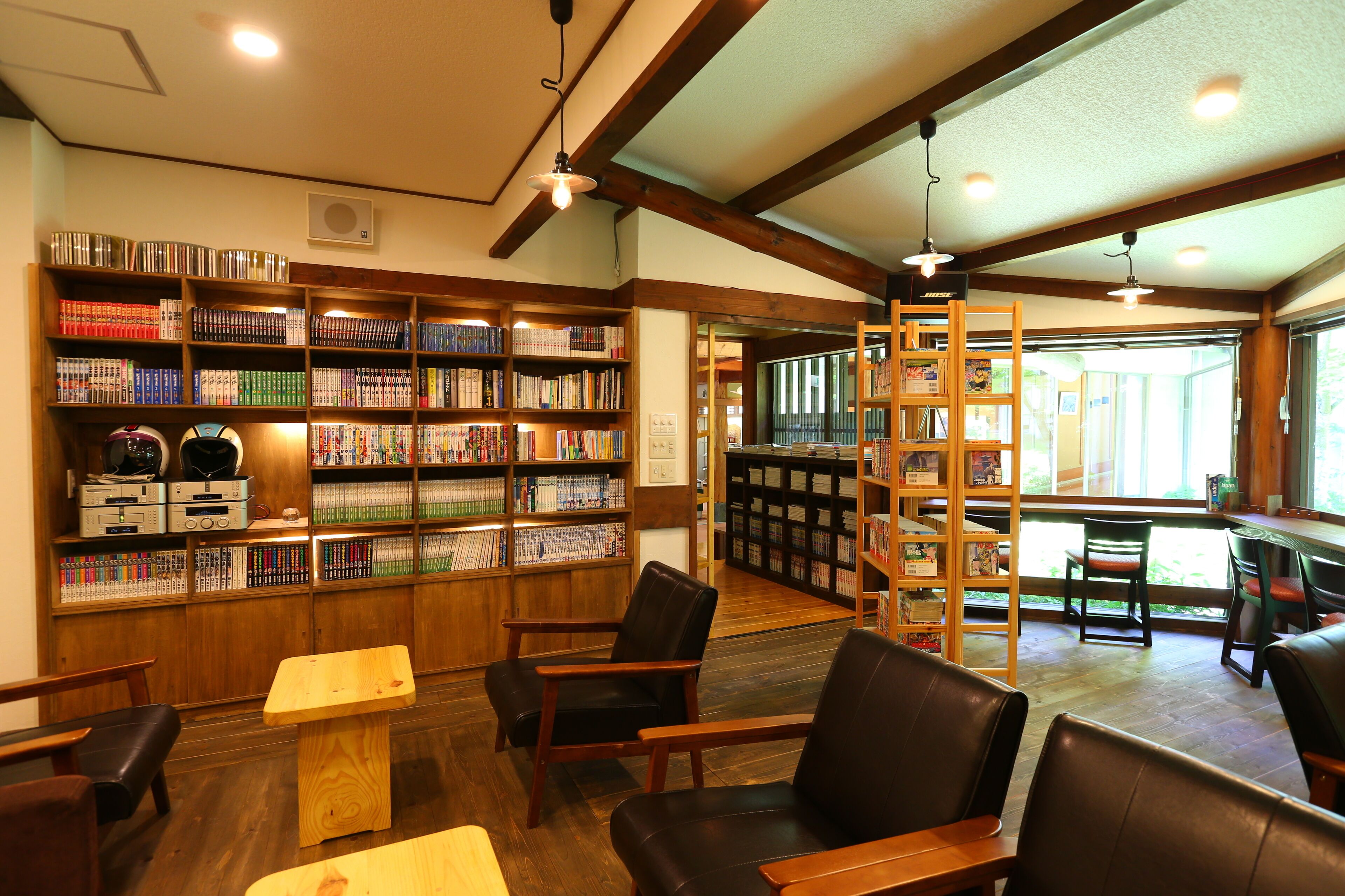 A library with wooden bookshelves, leather chairs, and a wooden table.