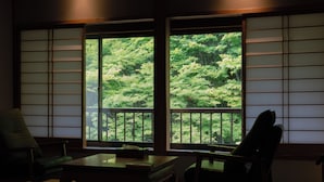 A traditional Japanese room with tatami flooring, a low table, and a chair. - Nukumorino-yado Komanoyu (Kiso)