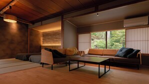 A traditional Japanese-style room with tatami flooring, a low table, and a sofa with cushions. - Nukumorino-yado Komanoyu (Kiso)