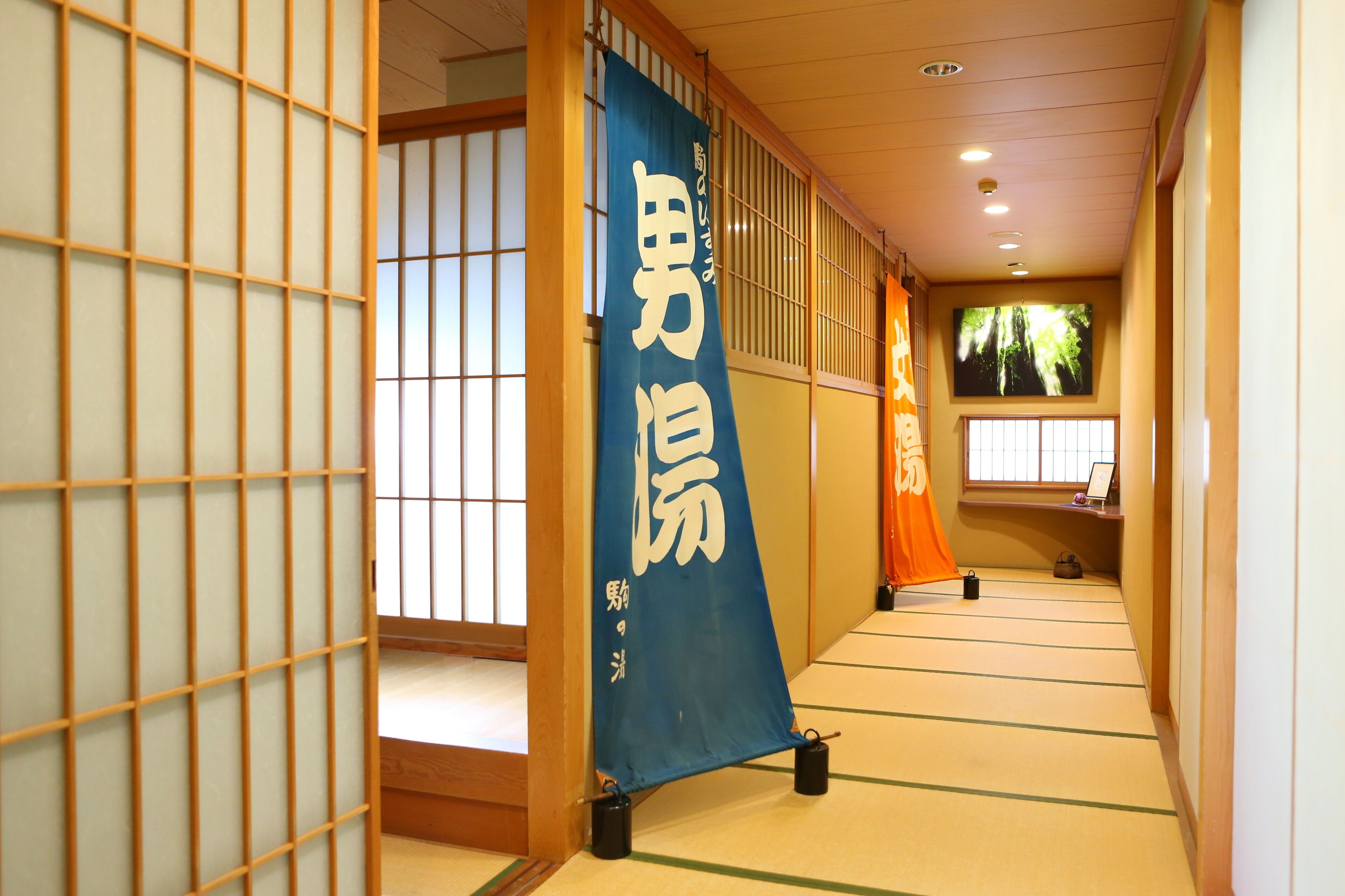 A traditional Japanese interior with tatami flooring, sliding doors, and a blue banner with white text.