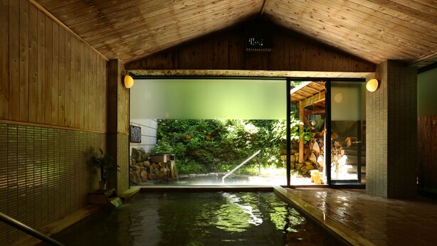An indoor swimming pool with wooden walls and a green wall with a waterfall feature. - Nukumorino-yado Komanoyu (Kiso)