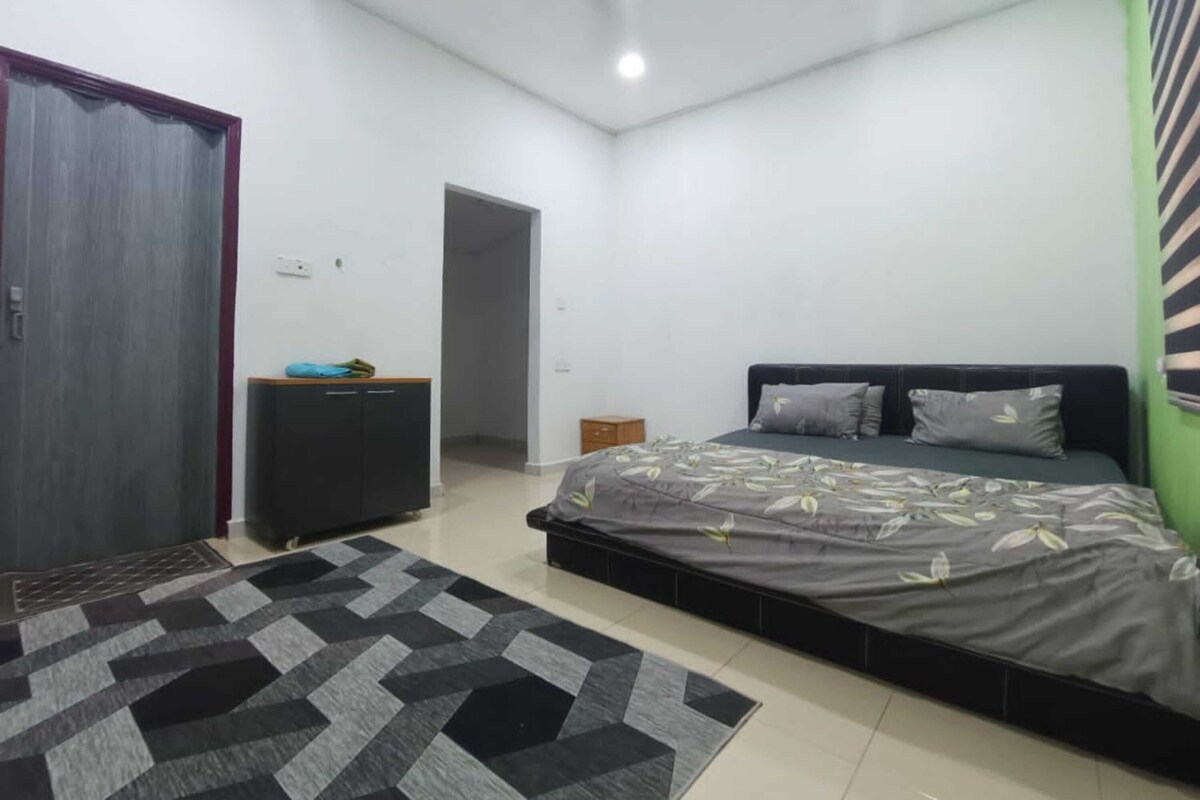 A bedroom with a bed, a wardrobe, a small table, and a door.