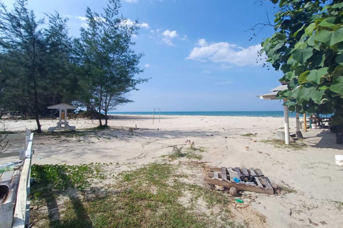 A beach with a gazebo, a small structure, and a wooden bench.