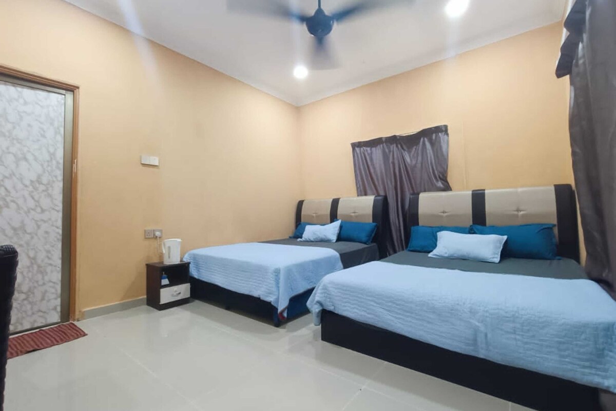 A hotel room with two beds, a ceiling fan, a nightstand, and a door.