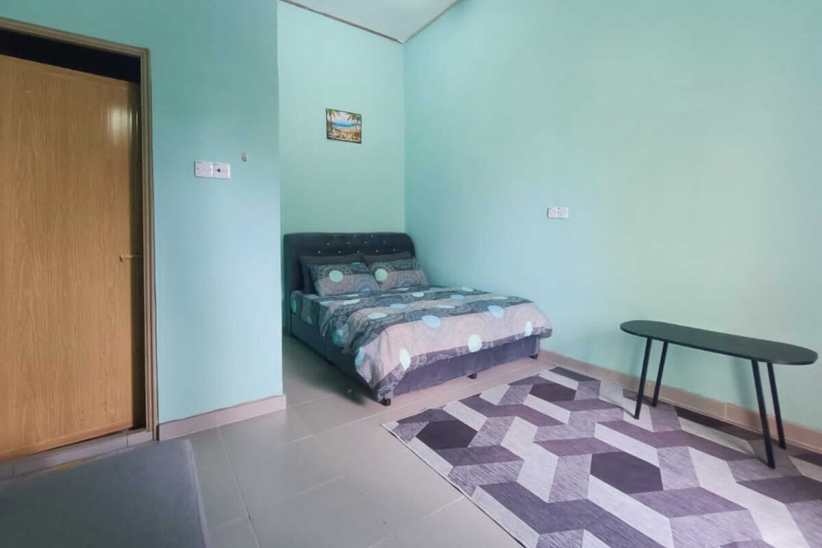 A bedroom with a bed, a small table, and a door.