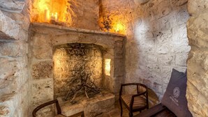 A stone fireplace with candles, two wooden chairs, and a bench. - Trullo La Sacchina in Ostuni (Ostuni)
