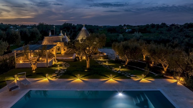 A luxurious villa with a swimming pool, stone architecture, and a well-lit garden at dusk. - Trullo La Sacchina in Ostuni (Ostuni)