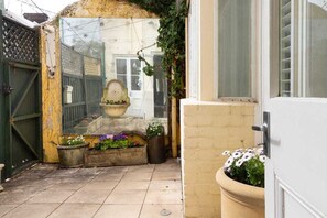 Step into a serene courtyard with a traditional gate, small fountain, and lush greenery.