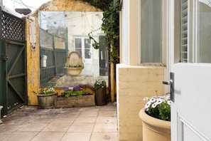 Step into a serene courtyard with a traditional gate, small fountain, and lush greenery.
