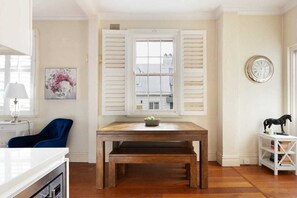 Cozy retreat with a wooden table, white shutters, and a comfortable chair.