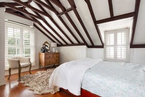 Cozy retreat with a sloped ceiling, featuring a comfortable bed, dresser, and chair.
