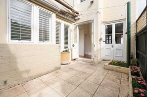 Stroll through the beautifully maintained grounds, featuring a paved patio and a charming entrance with a potted plant.