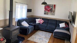 Een woonkamer met een modulaire bank, een open haard, een vloerkleed en een schilderij aan de muur.