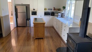 Een moderne keuken met witte kastjes, een houten eiland, roestvrijstalen apparatuur en een zwart fornuis.