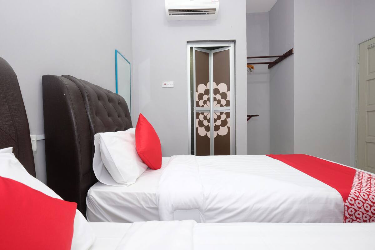 A hotel room with two beds, a wardrobe, and a door with a decorative pattern.
