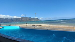 A swimming pool with a view of the beach and mountains. - Oppulent Apartment on the Beach (Cape Town)