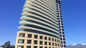 A modern high-rise building with a curved facade and multiple balconies. - Oppulent Apartment on the Beach (Cape Town)