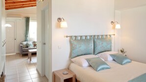 Una camera da letto con un letto, comodini e una porta che dà su un'altra stanza.