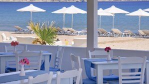 Un ristorante sulla spiaggia con mobili bianchi e cuscini blu, con vista sul mare.