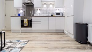 Une cuisine moderne avec des armoires blanches, une hotte de cuisinière en acier inoxydable et un éclairage sous les armoires.