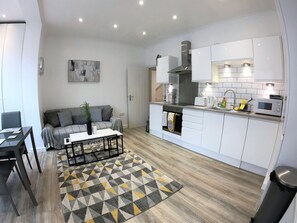 A modern kitchen with white cabinets, a built-in oven, and a microwave. - Harwoods Road Watford Apartments (Watford)