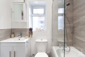 Une salle de bain moderne équipée d’un lavabo, de toilettes et d’une douche.
