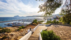 Vista costera con un puerto deportivo, una playa de arena y una escalera que baja hacia el agua.