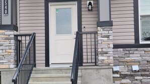A residential building with a front entrance, stone steps, and a mailbox. - Creekwood Luxury 1 Bed Lower Level Suite (Edmonton)