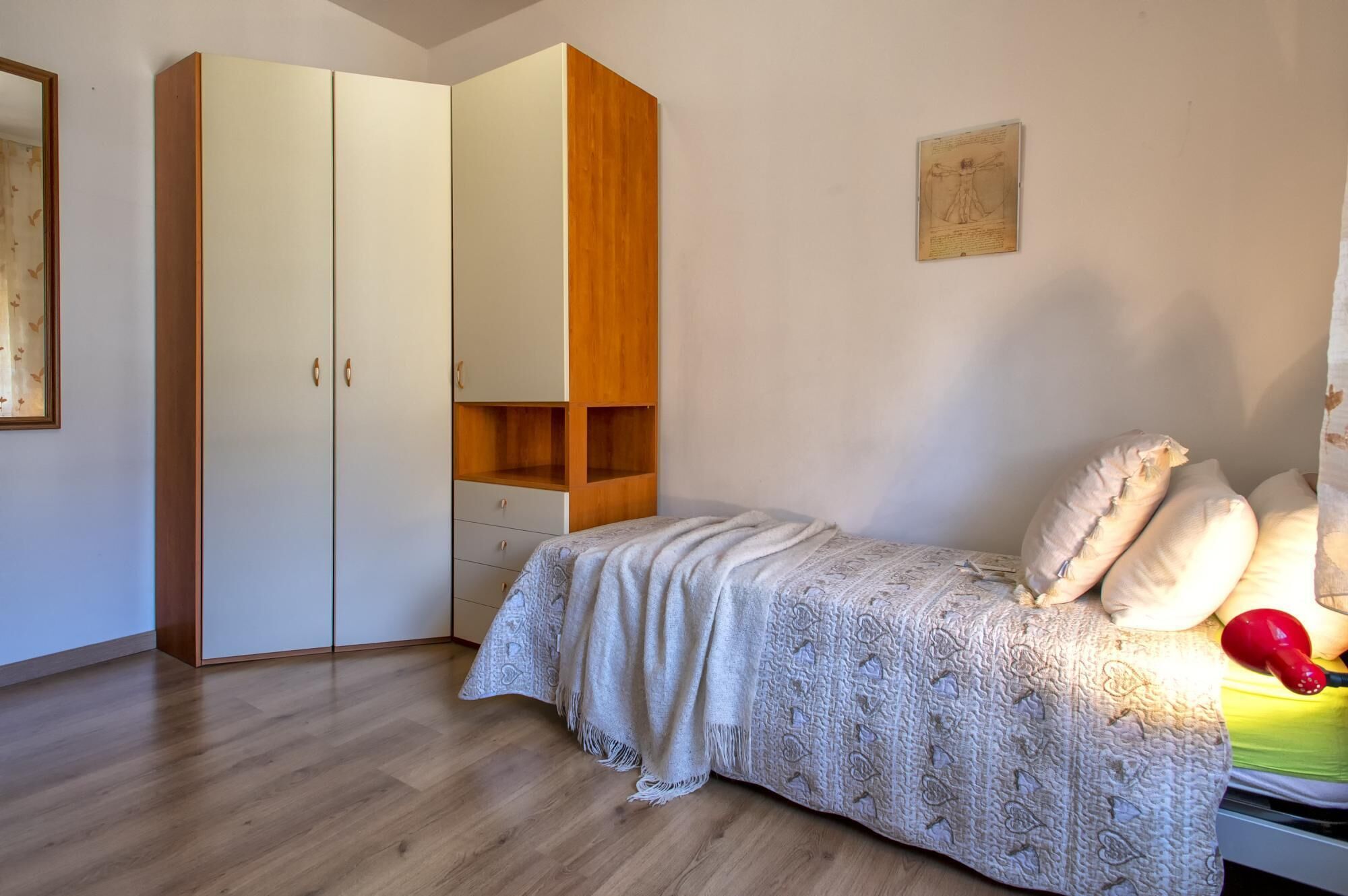 A bedroom with a bed, a wardrobe, and a small shelf unit.