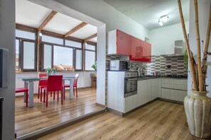 Una cocina moderna con armarios rojos, un microondas y una estufa. Hay una zona de comedor con sillas rojas y una mesa.