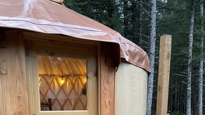 Una cabaña de madera con un letrero que dice 'WELCOME', un vidrio y una terraza con muebles de mimbre.